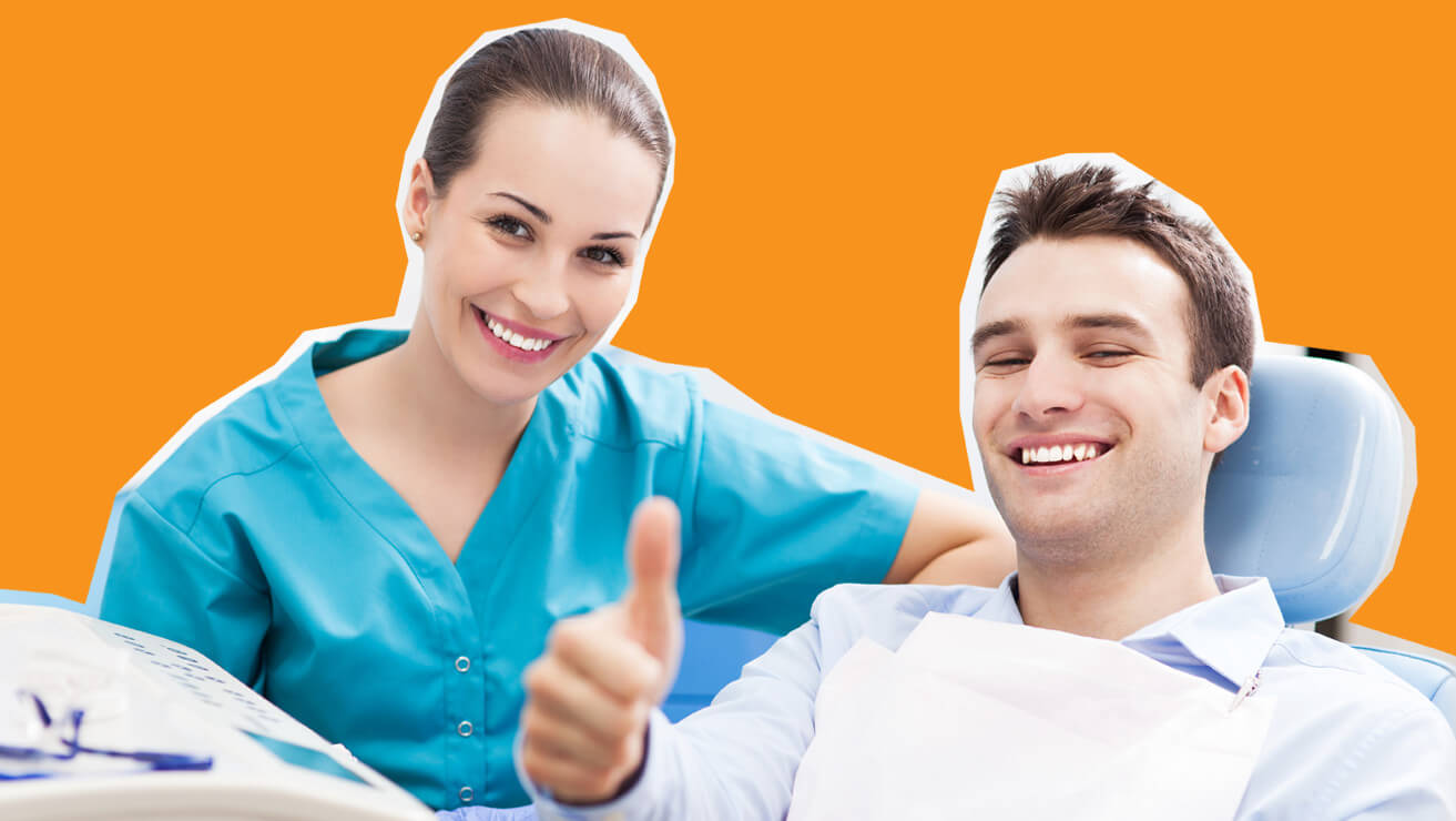 férfi páciens a fogorvosi székben ülve mosolyog és a hüvelykujját mutatja, a fogorvos nő mellette mosolyogt