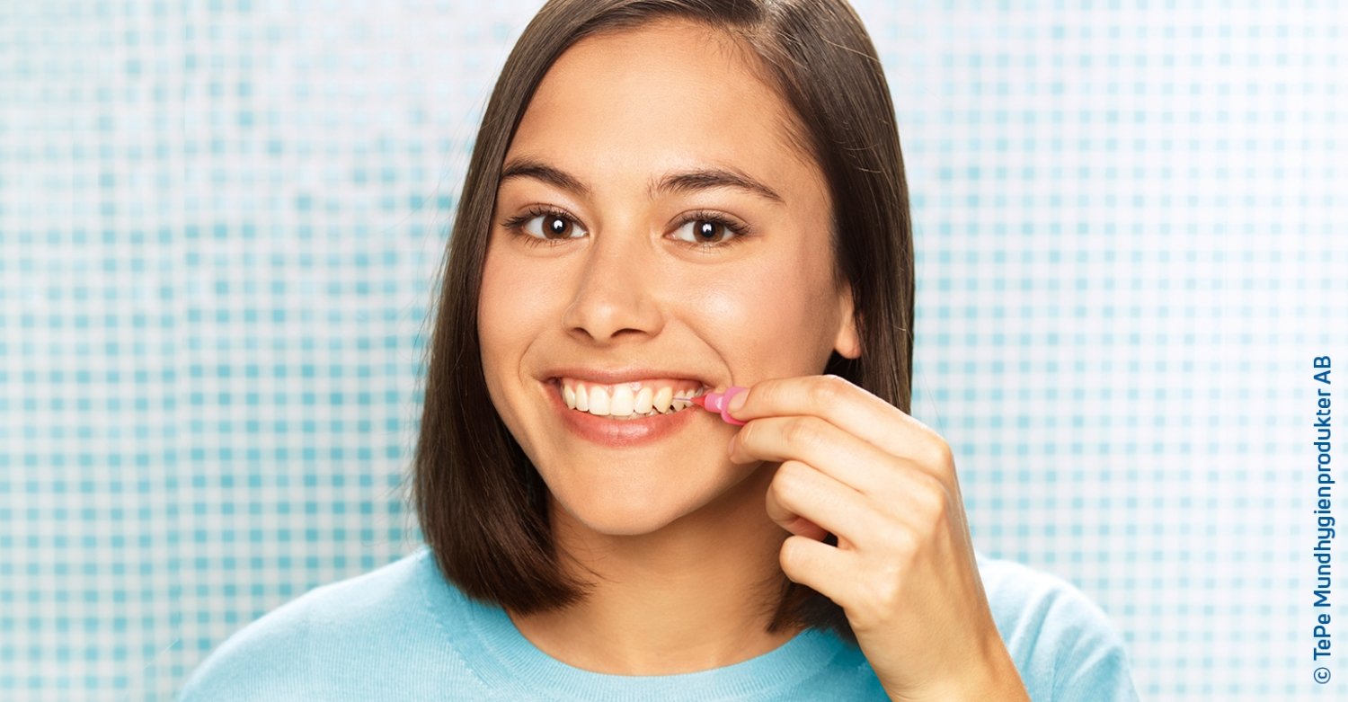 Mosolygó nő fogköztisztítókefét használ a fogain a fürdőszobában